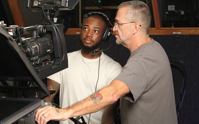 Young student learning how to operate a studio camera