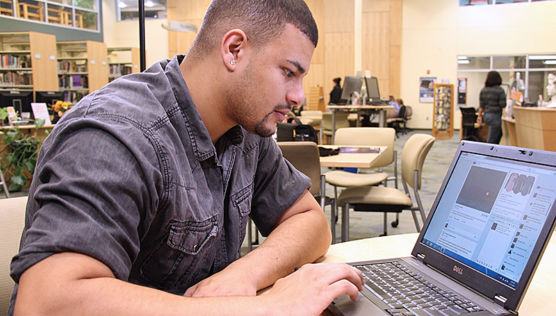 Cayuga student in the library on a laptop computer