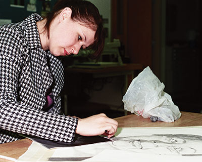 Art student working on her charcoal drawing in class