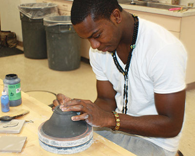 Student making a clay pot in pottery class